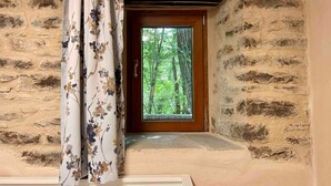 Ein Zimmer mit Steinwänden und einer Holztür, die in einen bewaldeten Bereich führt.