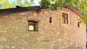 Ein Steinhaus mit einem kleinen Fenster und einem größeren Fenster mit Holzrahmen.