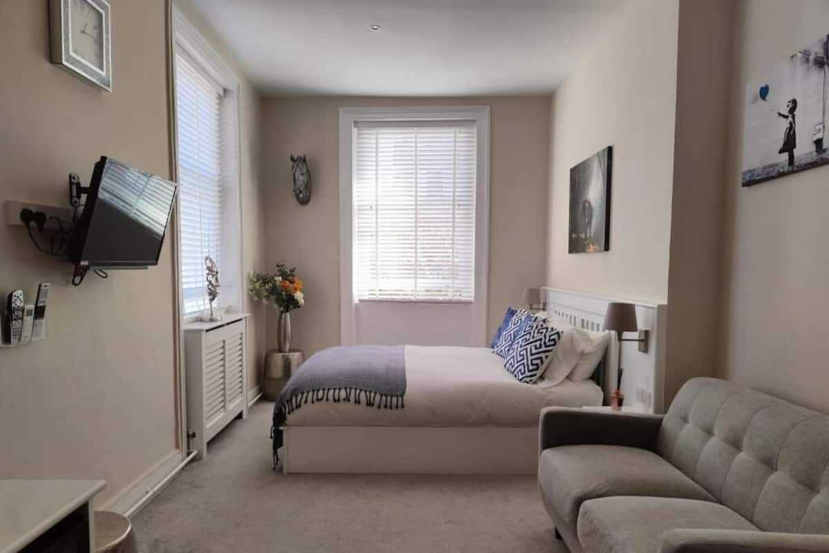 Un dormitorio con cama, sofá, televisor y un cuadro en la pared.
