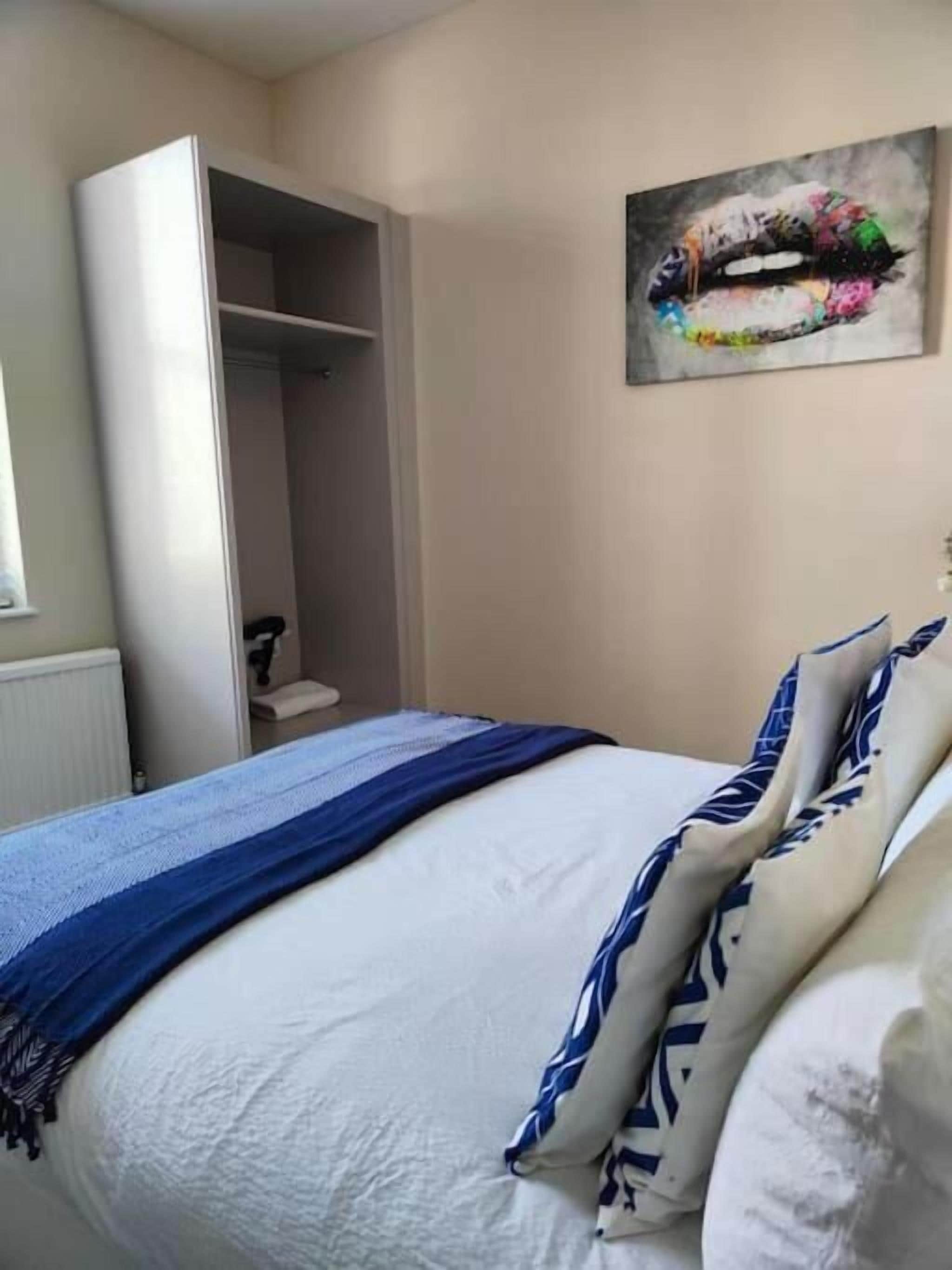 A bedroom with a bed, a wardrobe, and a painting on the wall.