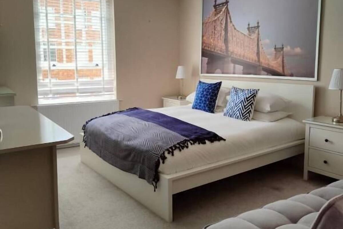 Un dormitorio con cama, mesitas de noche, escritorio y una silla.