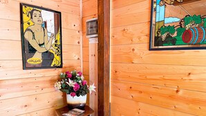 Ein Holzinterieur mit einem Bilderrahmen mit dem Porträt einer Frau, einer Vase mit Blumen und einem Holzschrank mit einer Zeitschrift.