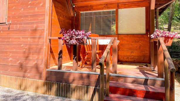 Eine Holzhütte mit Veranda, einem Fenster mit Jalousien und einem Nummernschild.