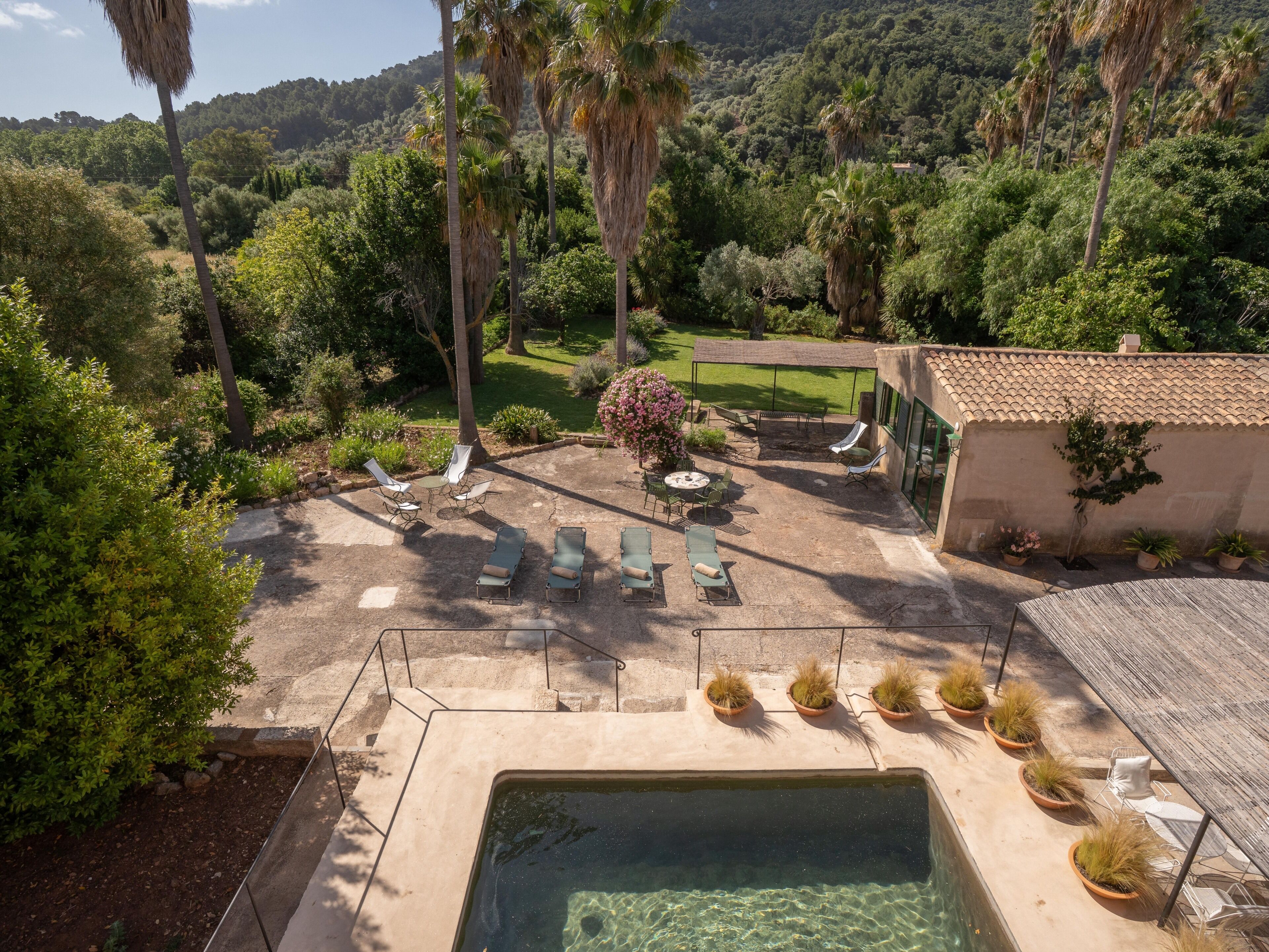 Un área de piscina con sillones de descanso, una mesa y una pérgola.