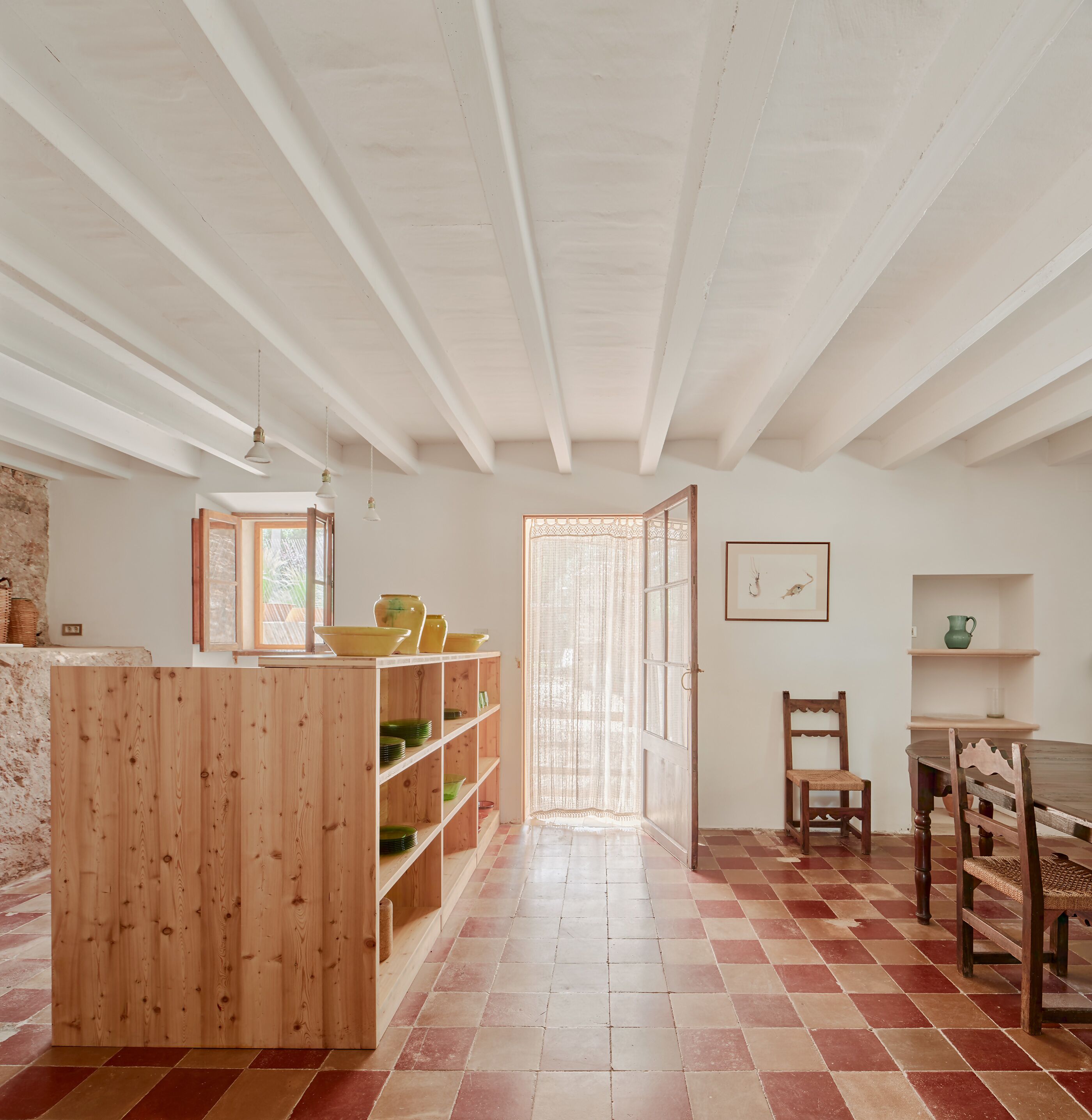A spacious kitchen with wooden beams, a tiled floor, and a dining area with a table and chairs.