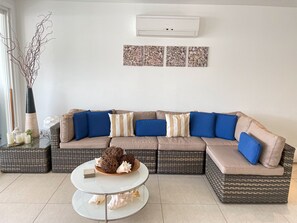 A modern living room with a sectional sofa, a glass coffee table, wicker baskets, and decorative items.
