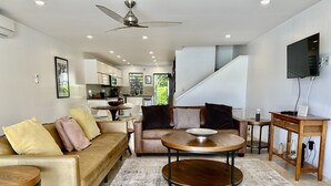 A modern living room with a sofa, coffee table, and TV stand. - Modern Waterfront Villa (Jolly Harbour)