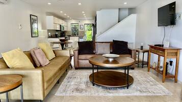 A modern living room with a sofa, coffee table, and TV stand.