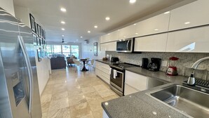 A modern kitchen with stainless steel appliances, a granite countertop, and a view to the dining area. - Modern Waterfront Villa (Jolly Harbour)
