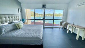 A bedroom with a bed, a desk, and a view of the sea. - Modern Waterfront Villa (Jolly Harbour)