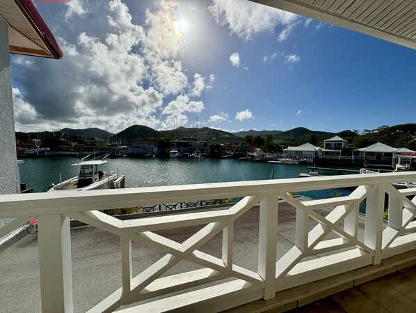 A marina with boats docked, a clear sky, and mountains in the background.