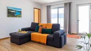 A modern living room with a grey sofa, a yellow throw blanket, and a painting of a landscape on the wall.