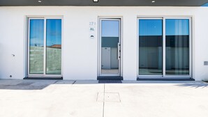 A modern building with two large glass doors, a clear sky, and a sign indicating room number 27A.