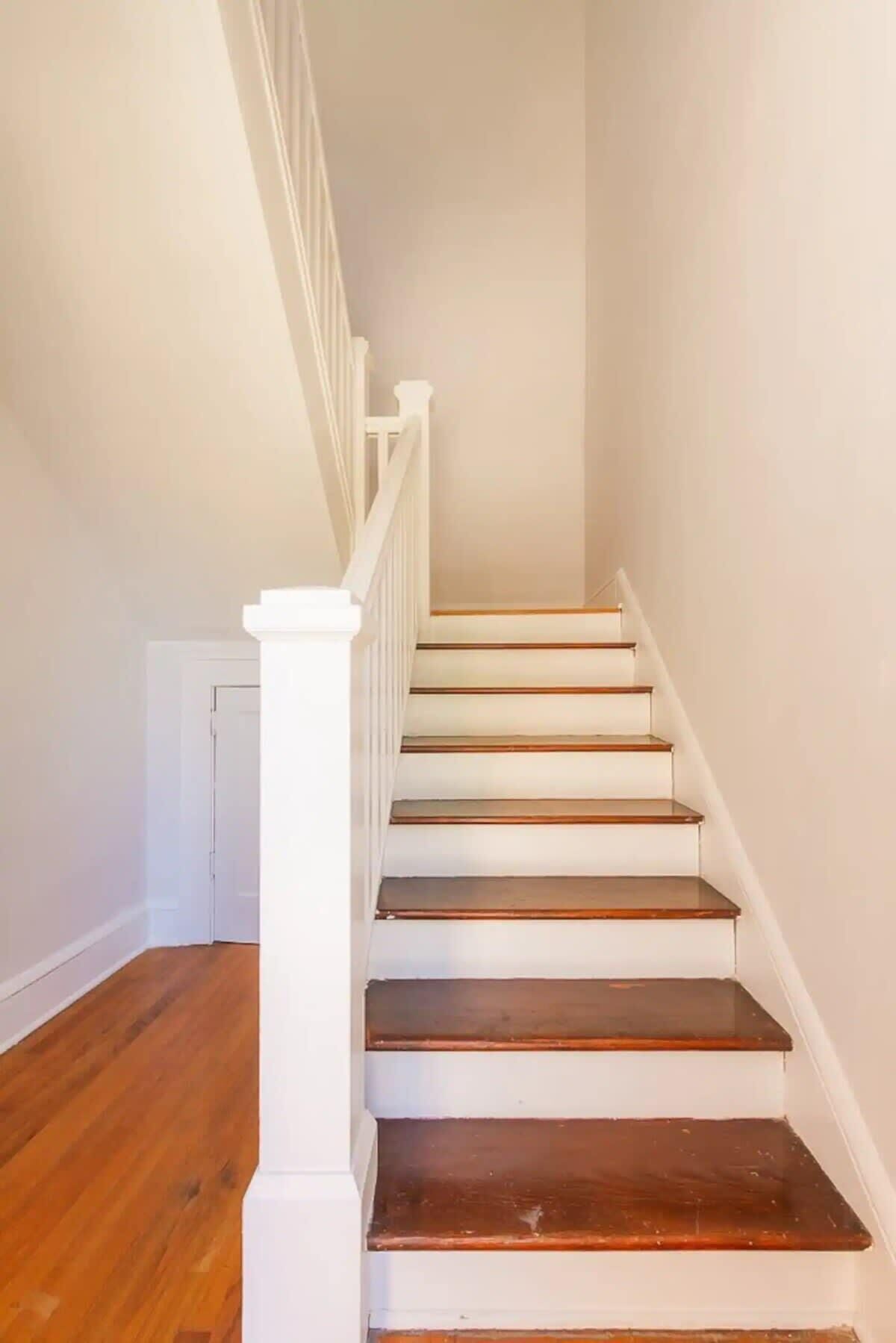A staircase with white railings and wooden steps leading to a door.