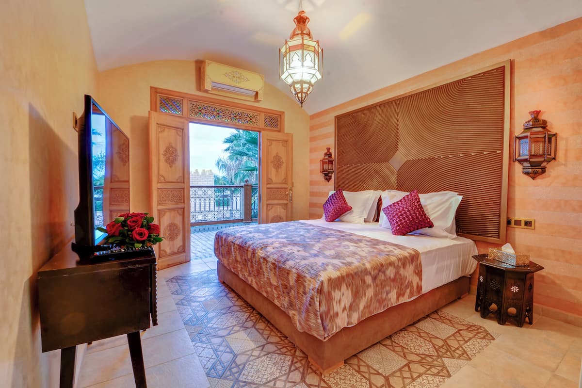 A bedroom with a large bed, a TV on a stand, and a decorative wall panel.