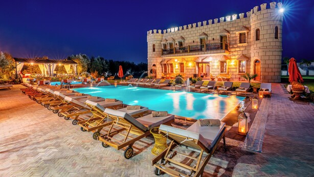 A castle-like hotel with a swimming pool, lounge chairs, and a well-lit outdoor area. - Atlas Castle Marrakech (Ghmate)