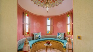 A room with a curved sofa, a small round table with a vase of flowers, and two ornate lanterns. - Atlas Castle Marrakech (Ghmate)