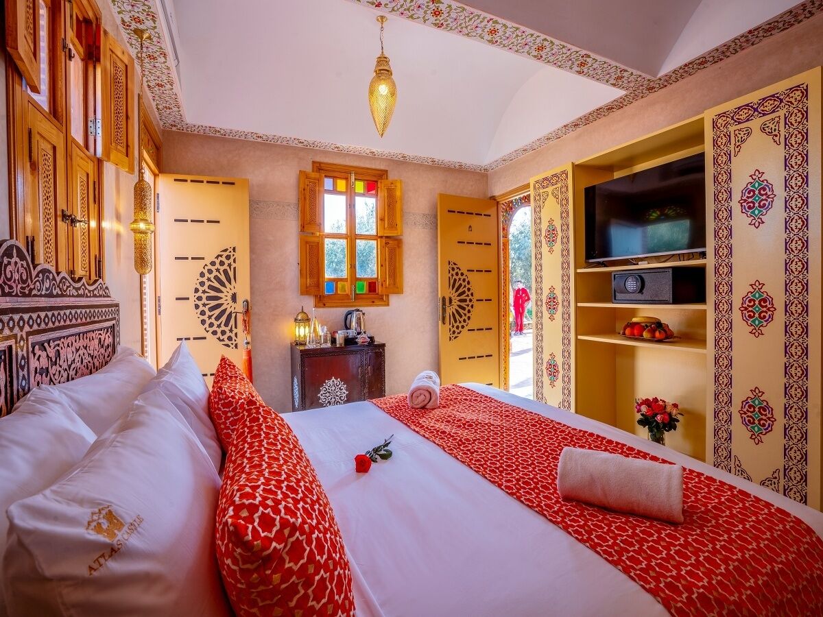 Habitació d'hotel amb dos llits, televisió, barra minibar i motius decoratius a la paret.