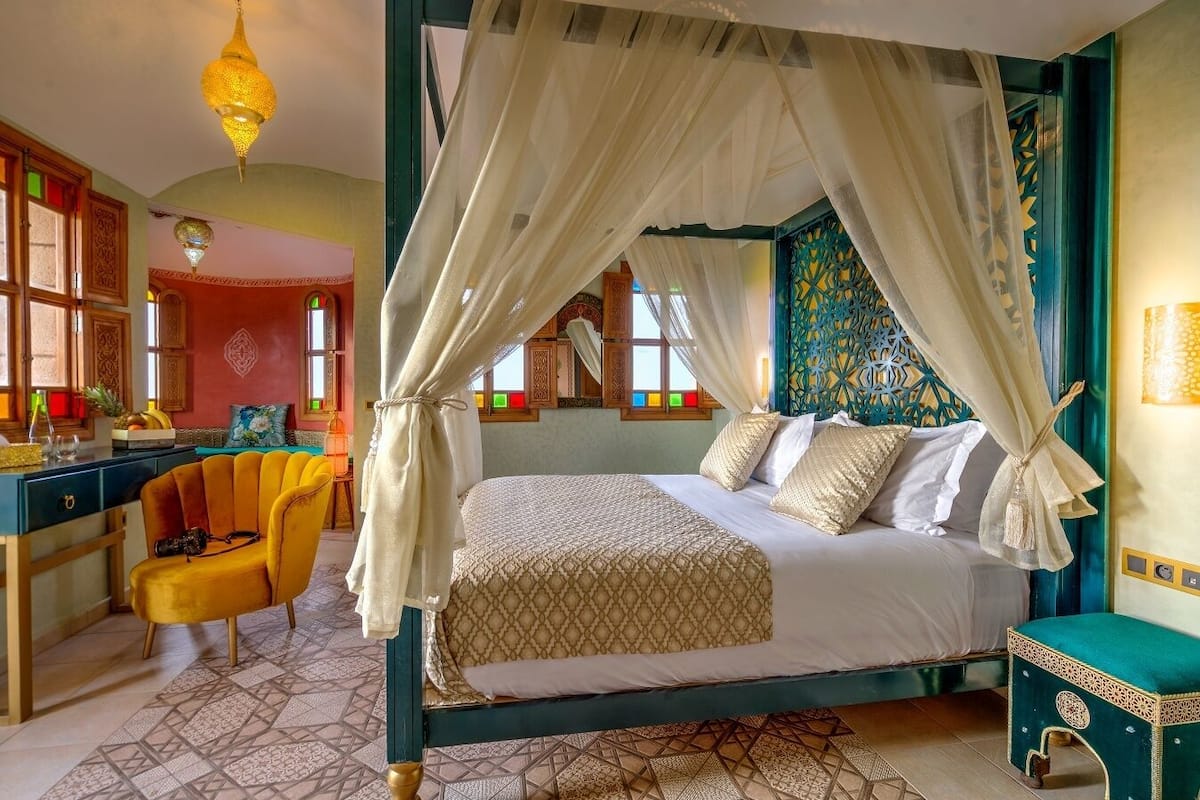 A four-poster bed with a canopy, a desk with a chair, and a patterned rug.
