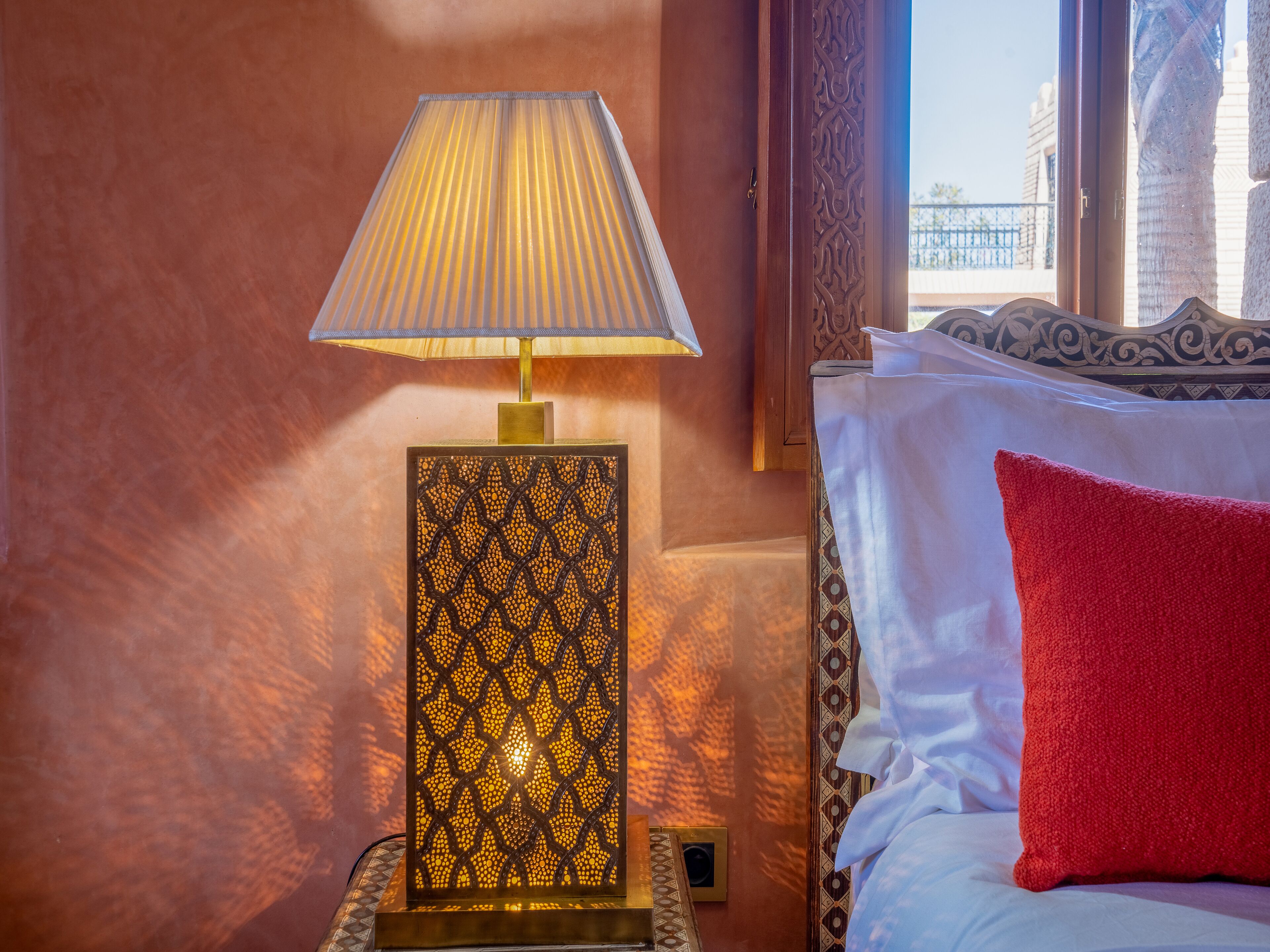 Una camera d'albergo con un letto, un comodino con una lampada e una finestra vista.