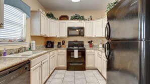 A kitchen with white cabinets, a black refrigerator, a stove, and a microwave.
