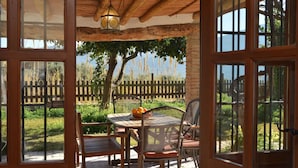 A patio with a table and chairs, a lantern, and a view of a wooden fence and trees. - Villa Tropical; High Standard Space Calm, Eco-Property Saltwater-Pool Child-Safe (Cortijo el Potro)