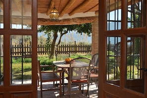 A patio with a table and chairs, a lantern, and a view of a wooden fence and trees. - Villa Tropical; High Standard Space Calm, Eco-Property Saltwater-Pool Child-Safe (Cortijo el Potro)