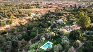An aerial view of a residential area with houses, a swimming pool, and surrounding greenery. - Villa Tropical; High Standard Space Calm, Eco-Property Saltwater-Pool Child-Safe (Cortijo el Potro)