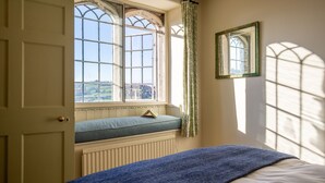 A room with a bed, a window with a view of the countryside, a radiator, and a mirror on the wall. - Rose Cottage, Rodborough - sleeps 6 guests  in 3 bedrooms (Stroud)