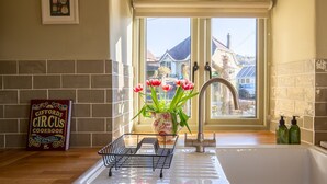 A kitchen with a window, a sink, a vase with tulips, and a cookbook on the counter. - Rose Cottage, Rodborough - sleeps 6 guests  in 3 bedrooms (Stroud)