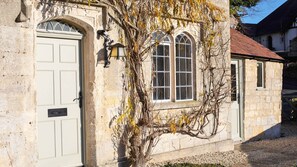 A stone building with a white door, a window with a grid pattern, and a wall-mounted light fixture.