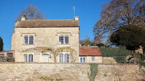 A stone building with a brick roof, multiple windows, and a stone wall in front.