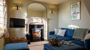 A cozy living room with a fireplace, blue sofa, and a framed quote on the wall. - Rose Cottage, Rodborough - sleeps 6 guests  in 3 bedrooms (Stroud)