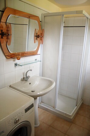Een badkamer met een wastafel, spiegel en douche.