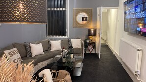 Een moderne woonkamer met een modulaire bank, een salontafel en een aan de muur bevestigde televisie.