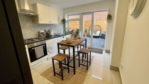 Een moderne keuken met witte kasten, een gasfornuis en een eethoek met een houten tafel en stoelen.