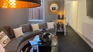 Een moderne woonkamer met een gebogen bank, een glazen salontafel en een decoratieve lamp.