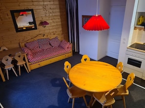 A cozy room with a wooden sofa, a round wooden table, and matching chairs. - Duplex apartment 8-10p in Risoul at the foot of the slopes ski area Vars Risoul (Risoul)