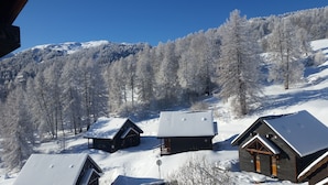 Un paysage montagneux enneigé, avec des chalets en bois et un télésiège.