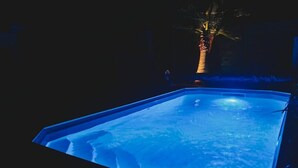 A swimming pool with a clear blue water surface, surrounded by a dark poolside area. - Le Grand Cottage Nature Piscine Chauffée Privée (Peyrole)
