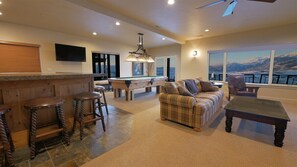 A spacious living area with a pool table, a sofa, and a bar area with stools.