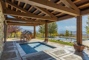 A covered outdoor area with a pool, patio furniture, and a view of mountains. - Luxurious Mountain Home with 7 BRs private hot tub (Eden)