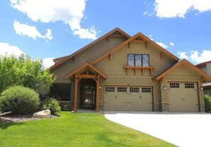 A two-story house with a garage, a covered entryway, and a well-maintained lawn. - Luxurious Mountain Home with 7 BRs private hot tub (Eden)