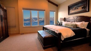 A bedroom with a large window, a bed, a nightstand, and a painting on the wall. - Luxurious Mountain Home with 7 BRs private hot tub (Eden)
