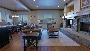 A spacious living room with a fireplace, large windows, and a dining area.