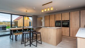 Une cuisine moderne avec des meubles en bois, un îlot central et un coin repas équipé de tabourets de bar.