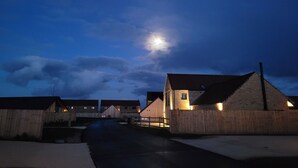 Een landelijke straat 's nachts met huizen en een houten omheining.