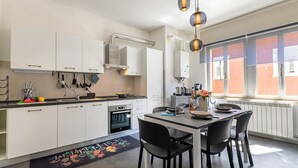 Une cuisine moderne avec des meubles blancs, une cuisinière, un four et un coin repas comprenant une table et des chaises.