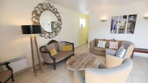 Una sala de estar con un sofá, un sillón, una mesa de centro y un espejo grande.