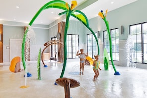 Kids can splash and play in this water play area featuring an arch structure with water jets and a central fountain.